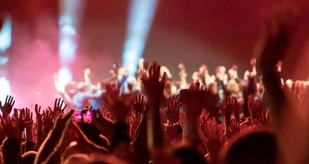 A crowd of people are raising their hands in the air at a concert.