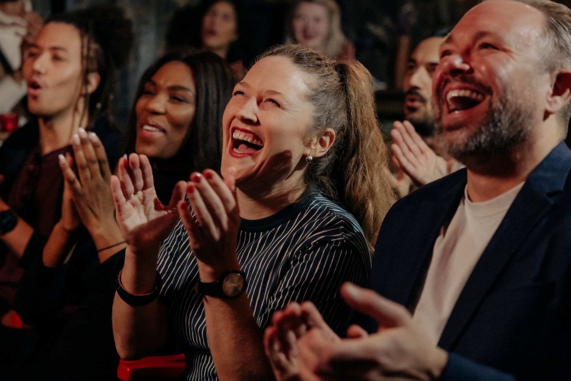 A group of people are laughing and clapping in a theater.