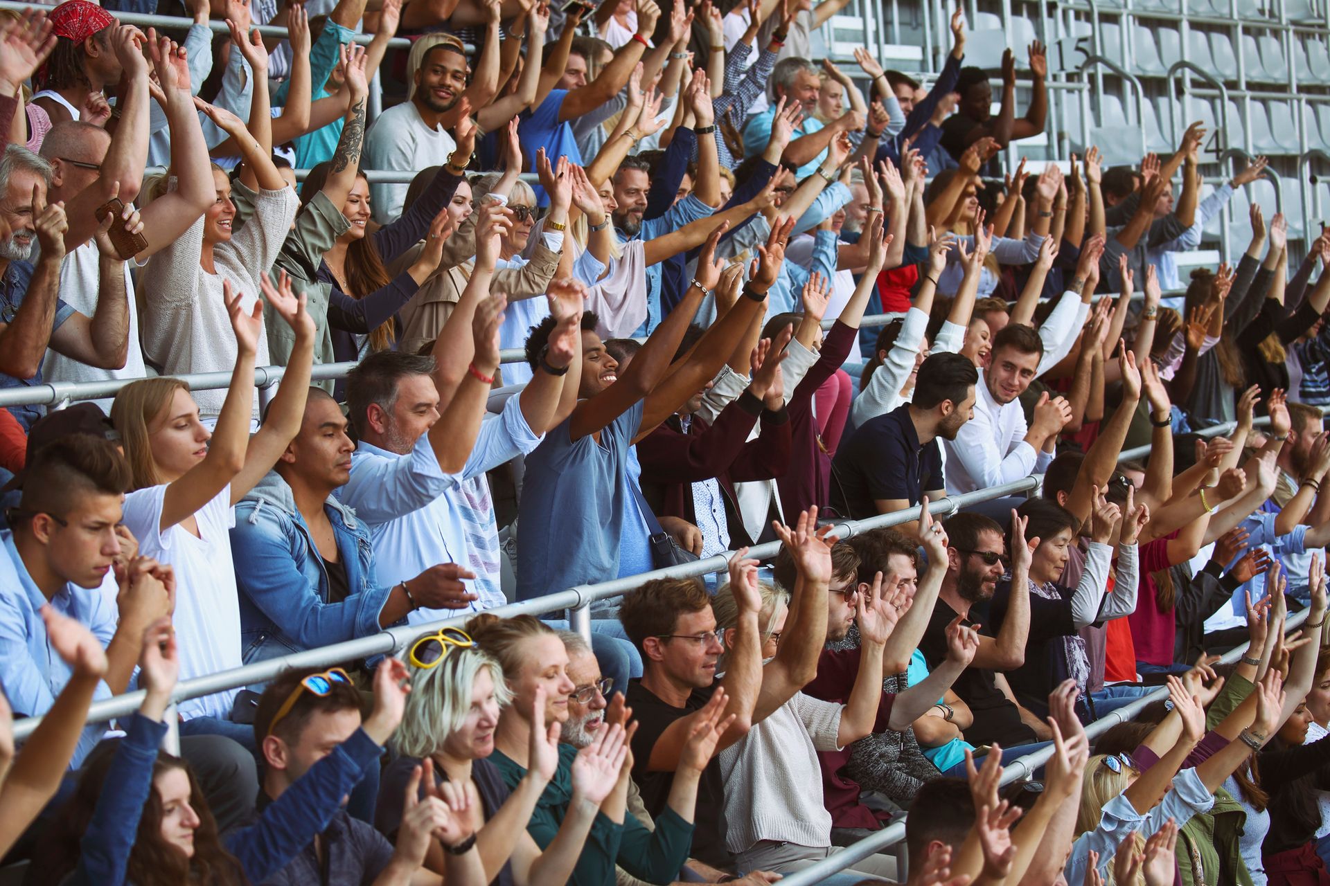 A crowd of people are sitting in a stadium with their hands in the air.