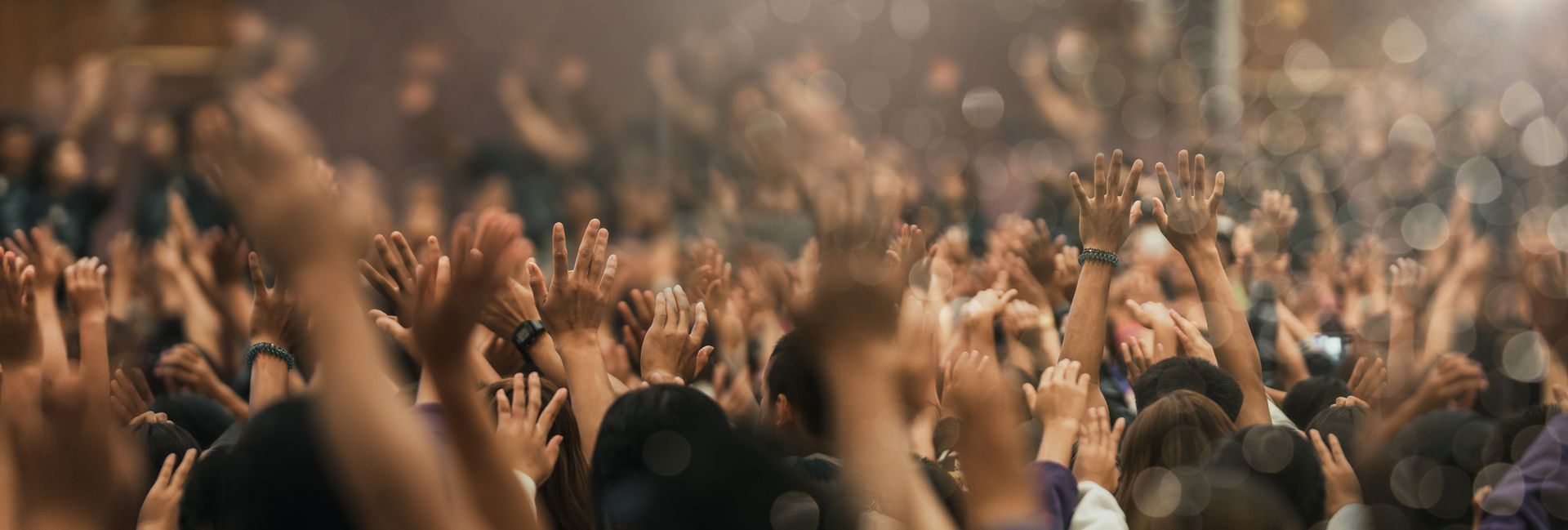 A crowd of people are raising their hands in the air at a concert.