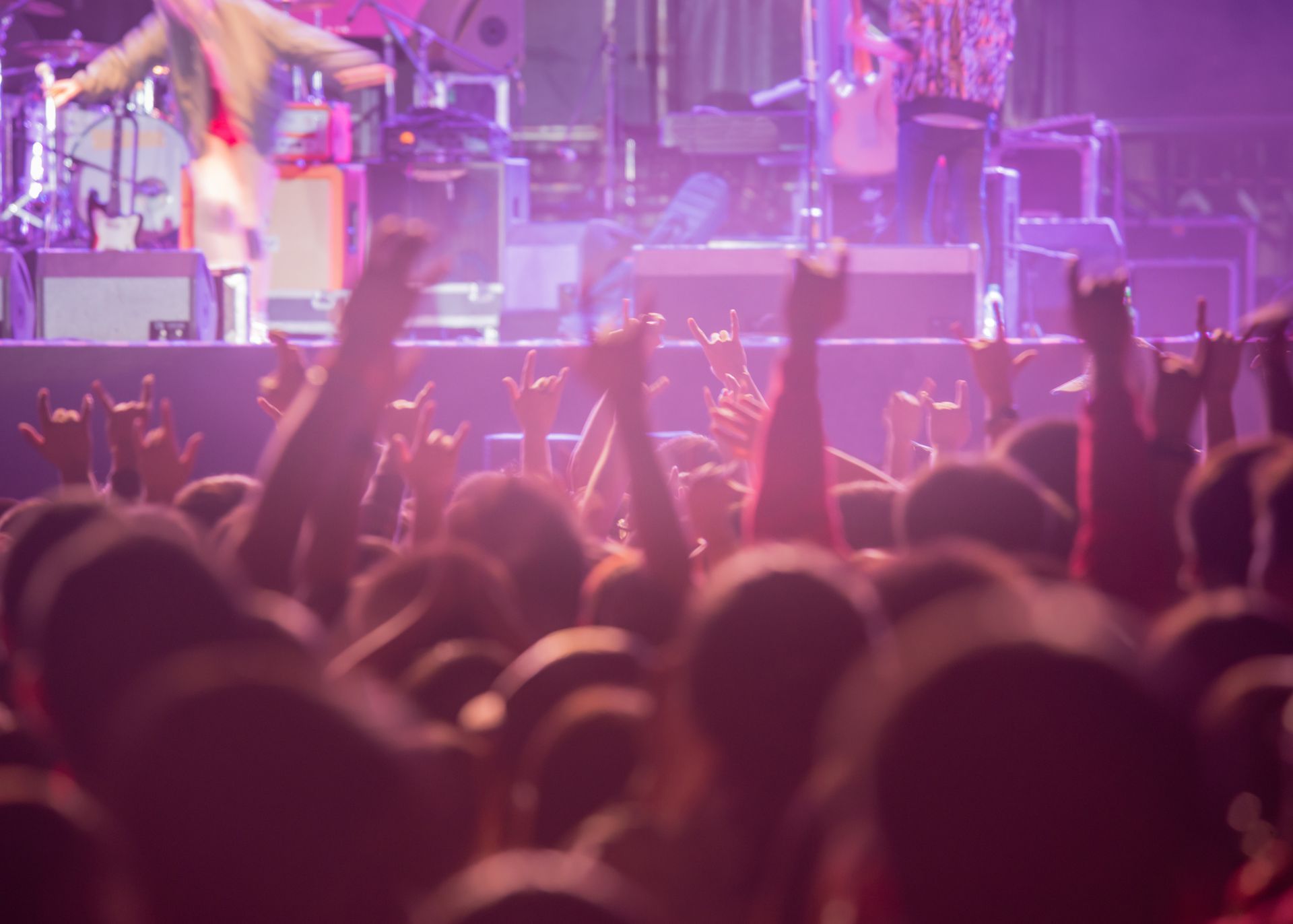 A crowd of people are raising their hands in the air at a concert.