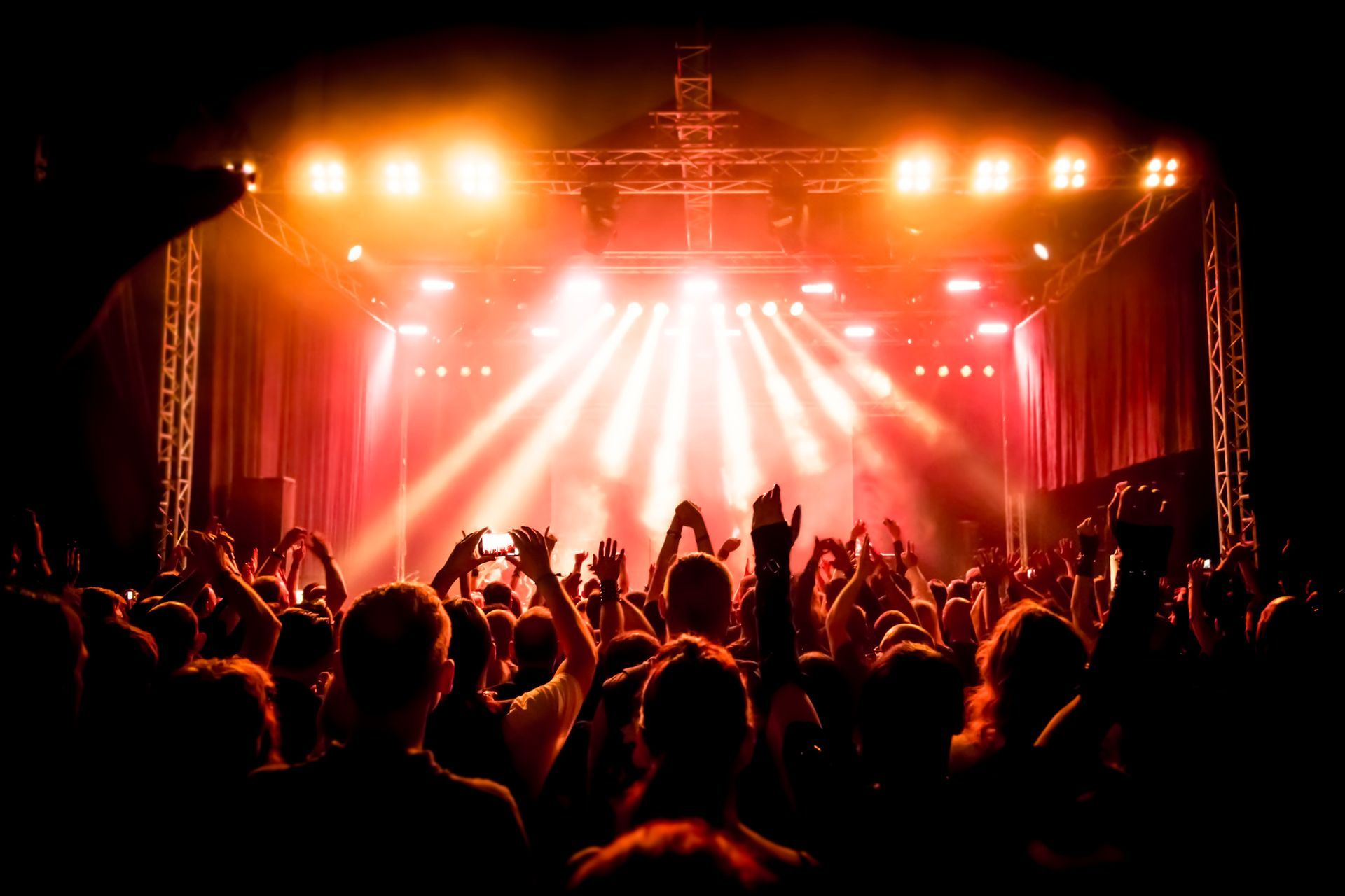 A crowd of people are standing in front of a stage at a concert.