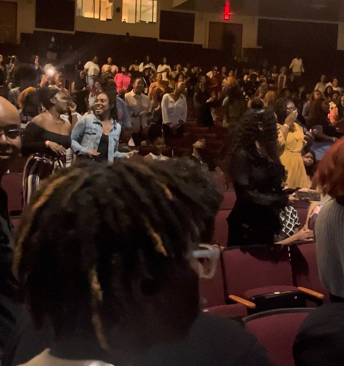 A crowd of people are sitting in a dark auditorium.