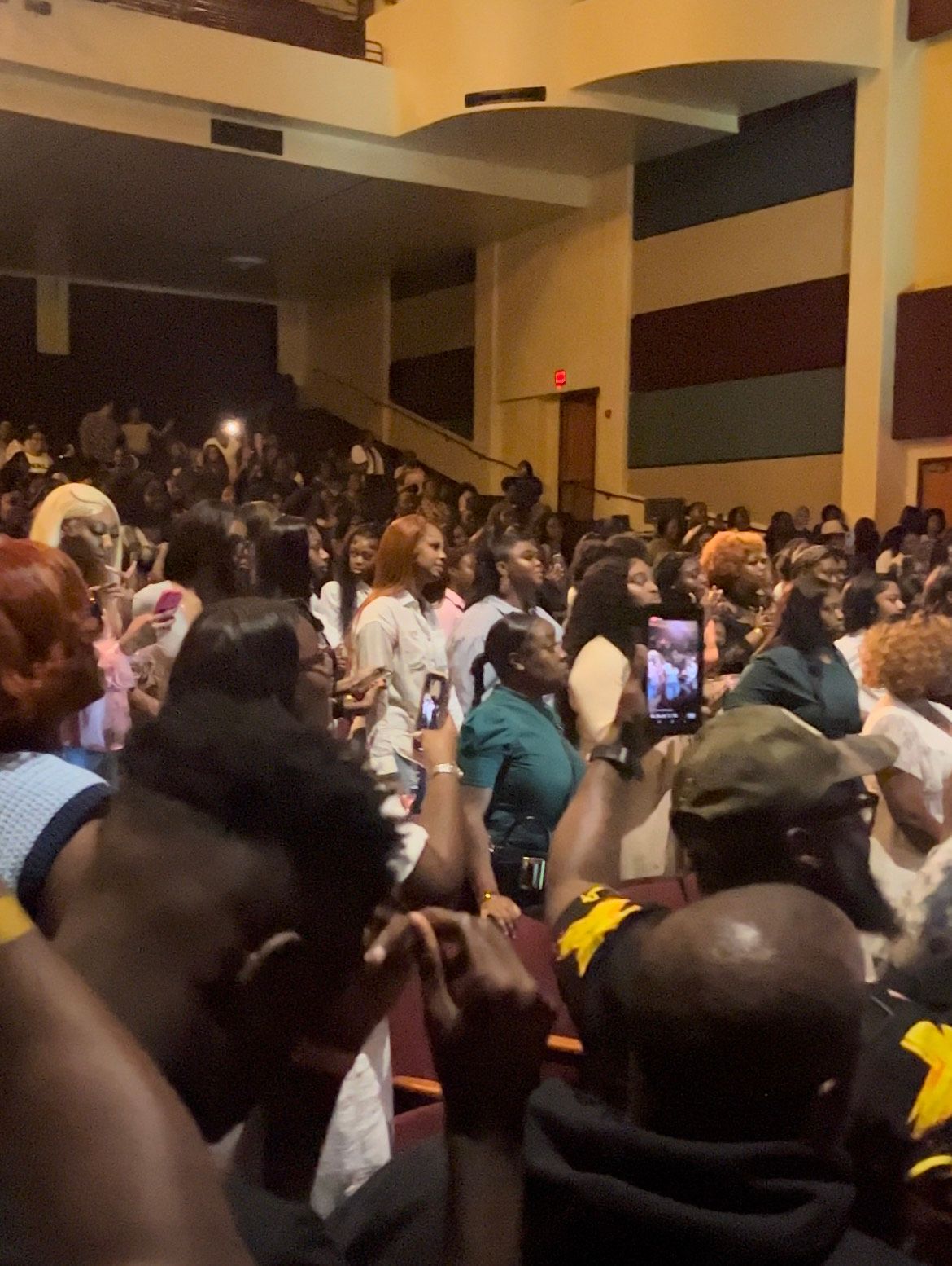 A crowd of people sitting in an auditorium watching a performance.