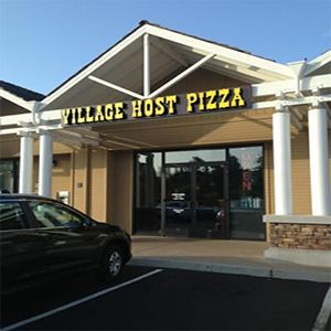 A car is parked in front of a village host pizza restaurant