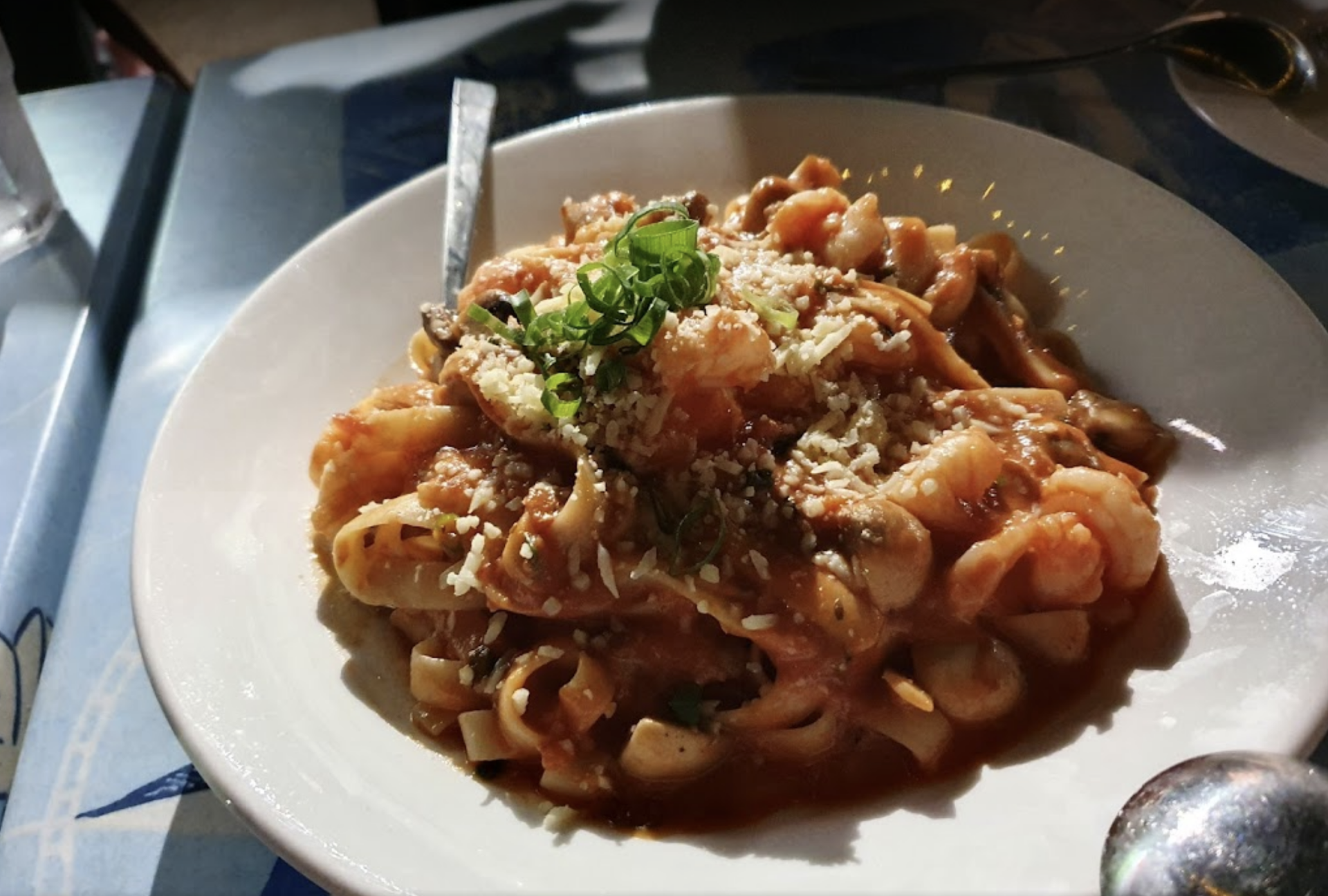 A white plate topped with pasta and sauce with a spoon in it — Bella M Pizzas in Bundaberg North, QLD