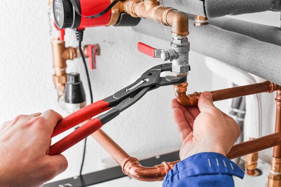 A plumber is fixing a pipe with a pair of pliers.