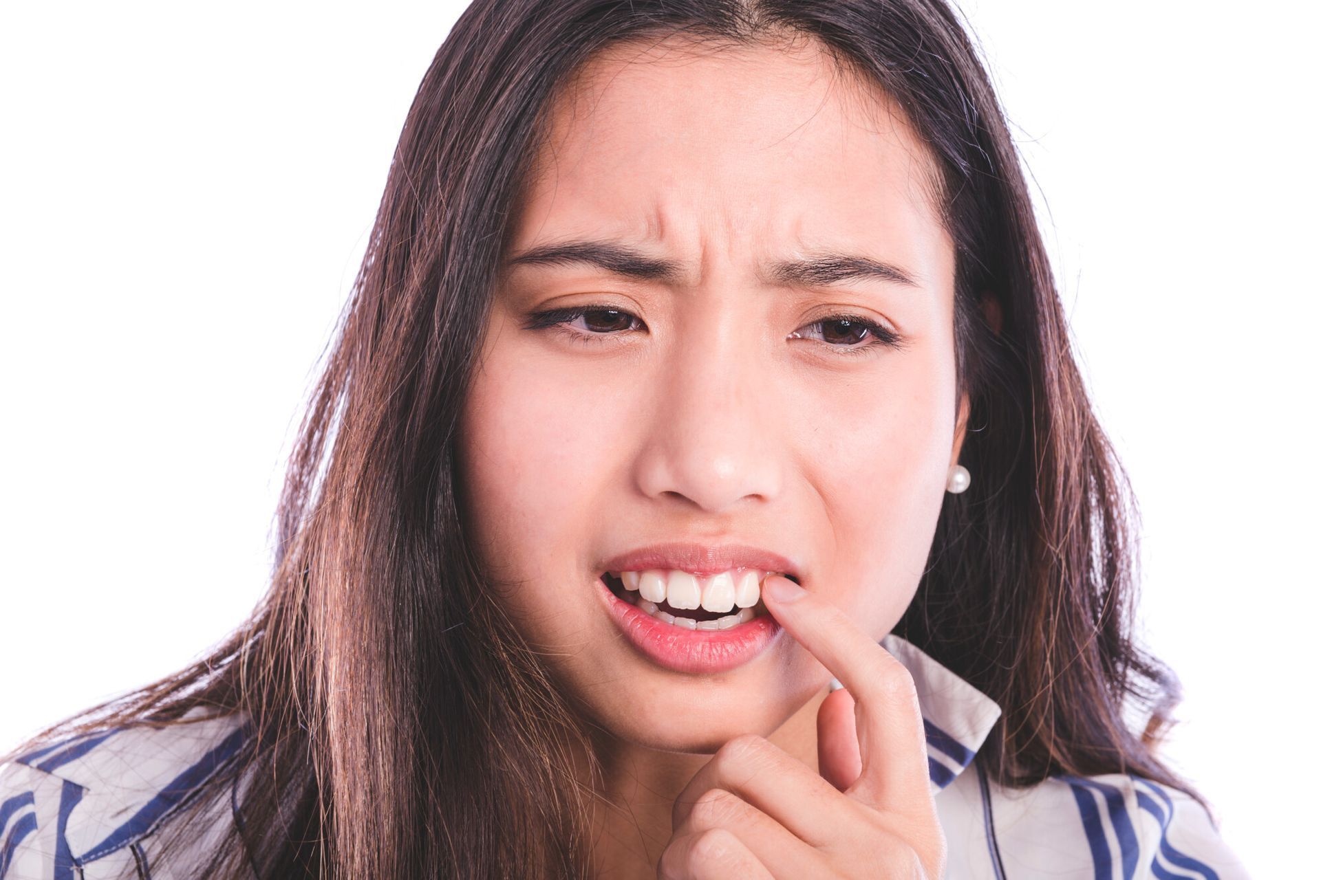 A woman is holding her finger to her mouth because she has a toothache.