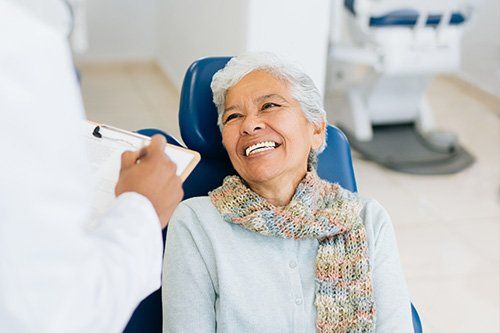 smile senior woman in orange ca dental chair