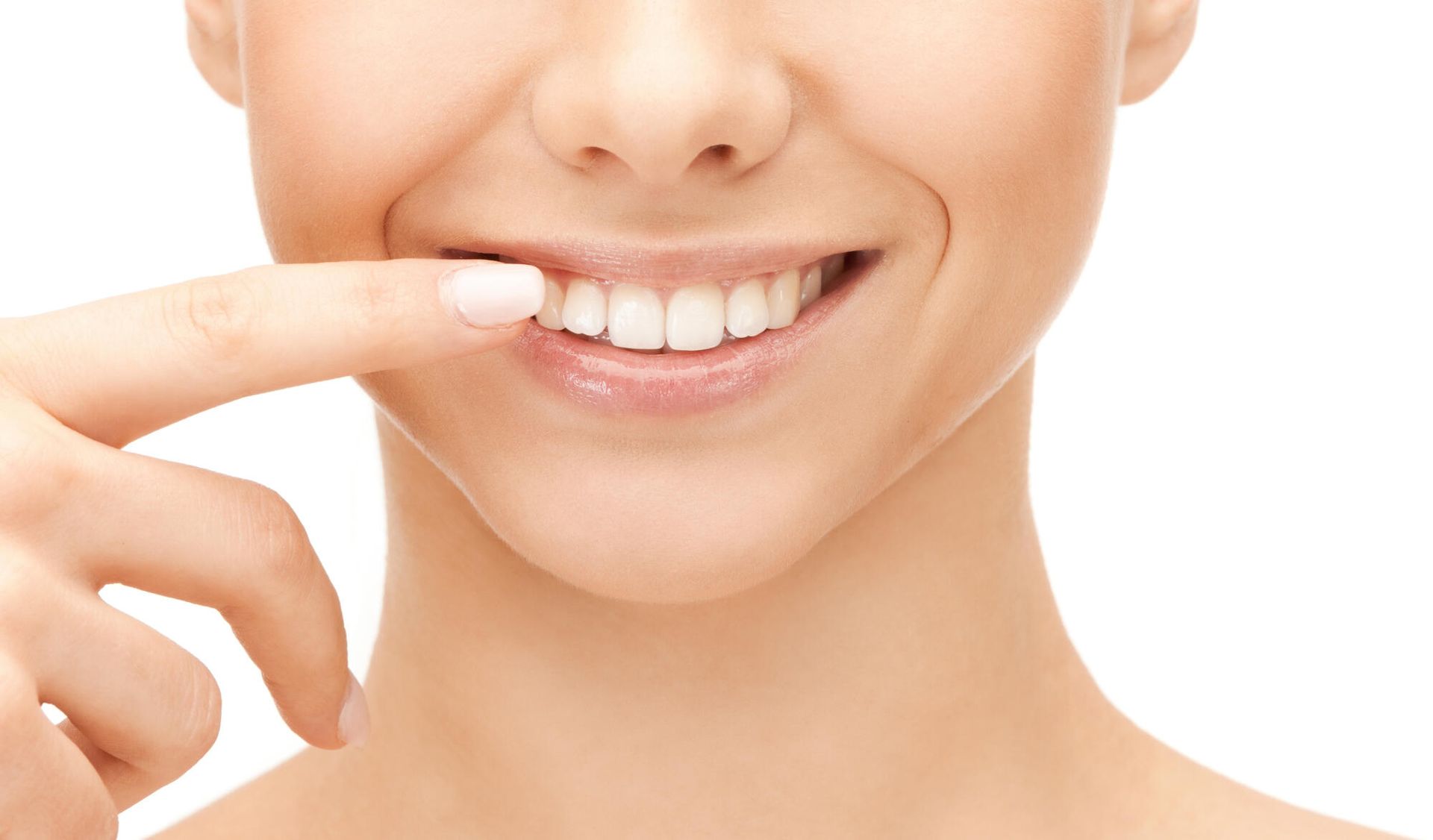 A woman is pointing at her teeth with her finger.