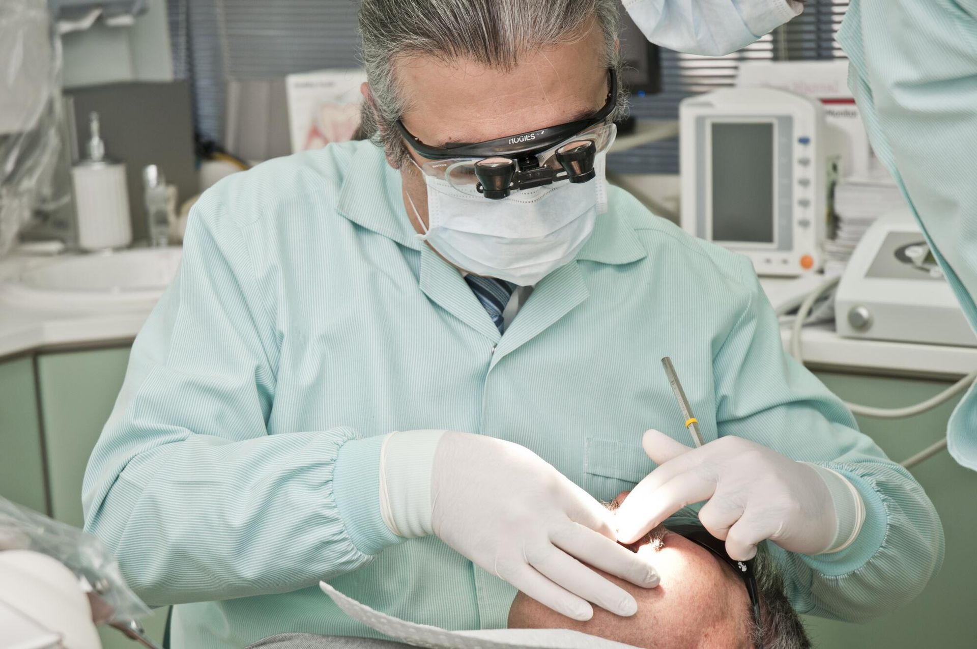A dentist is examining a patient 's teeth in a dental office.