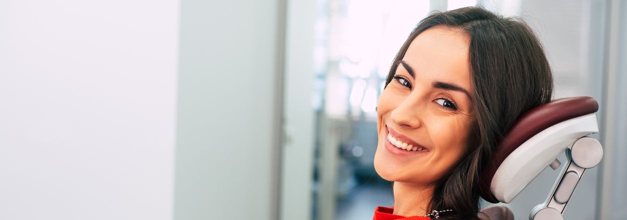 A doctor wearing a mask examines a child with the child's mother nearby.