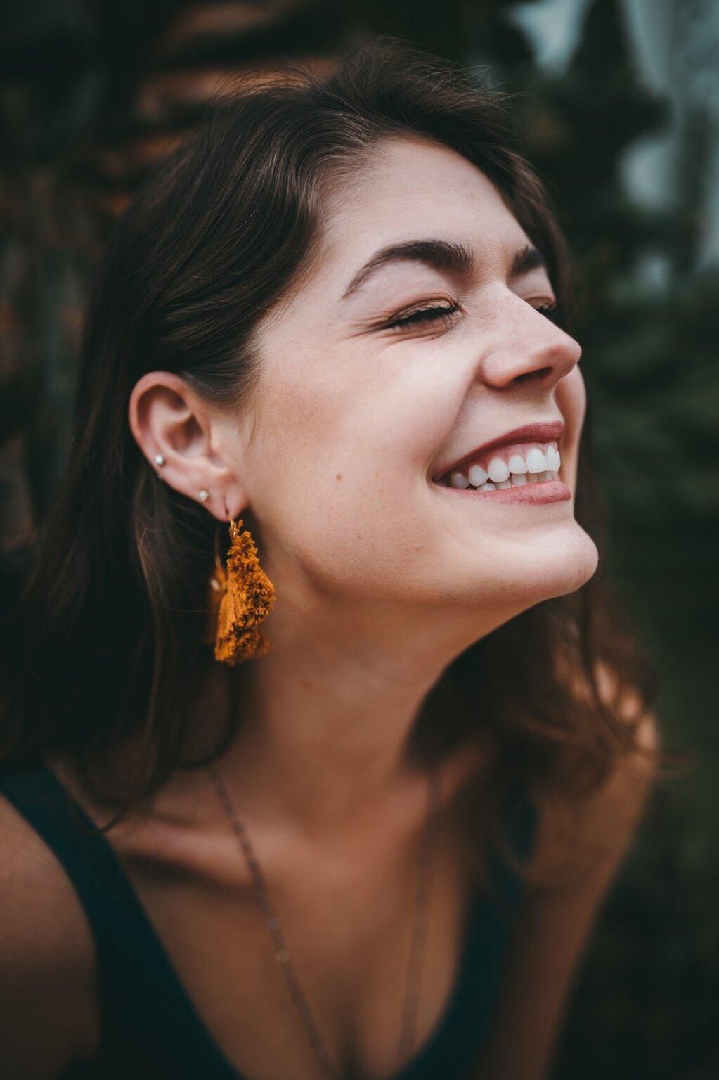 A close up of a woman wearing earrings and smiling.