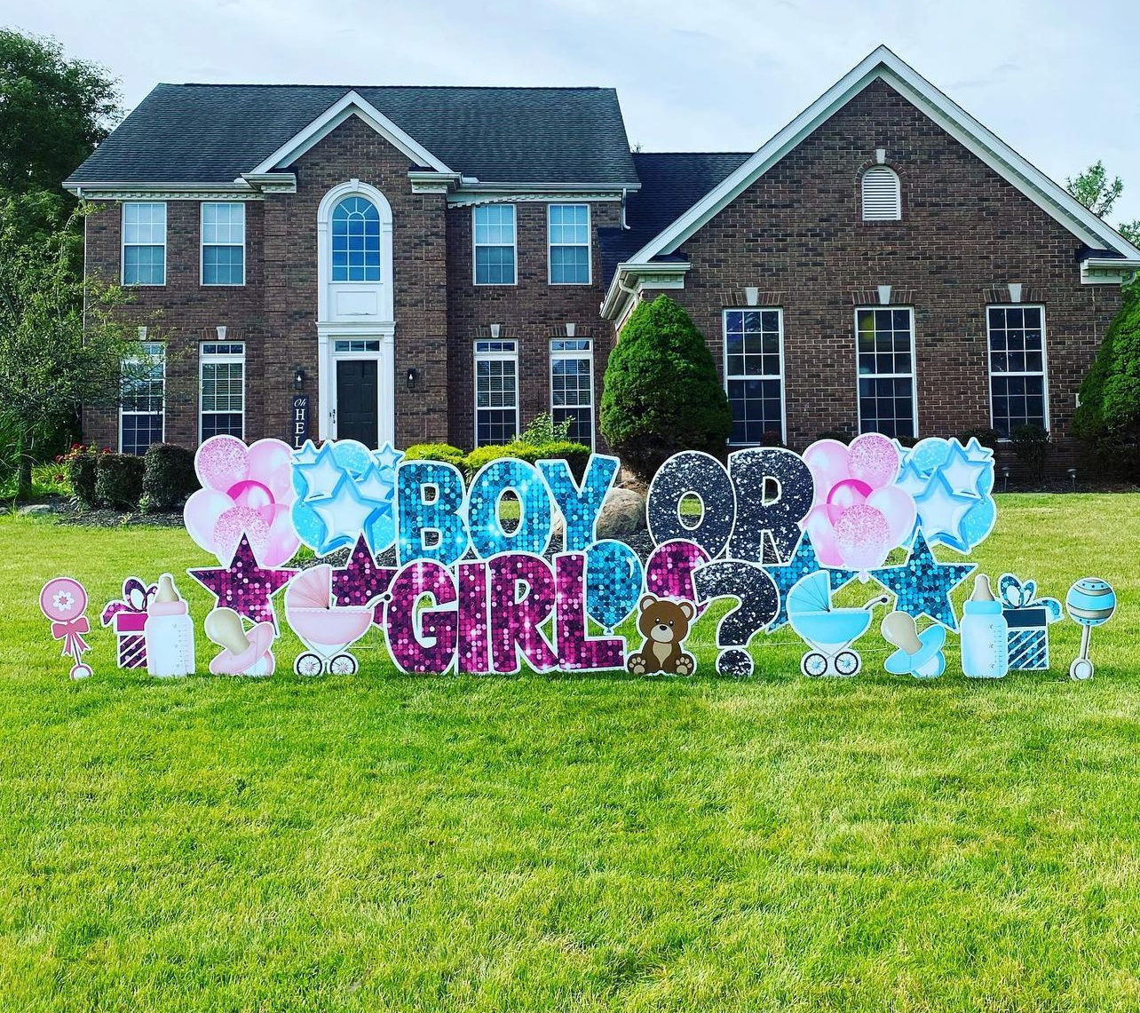 A boy or girl sign is sitting in front of a brick house.