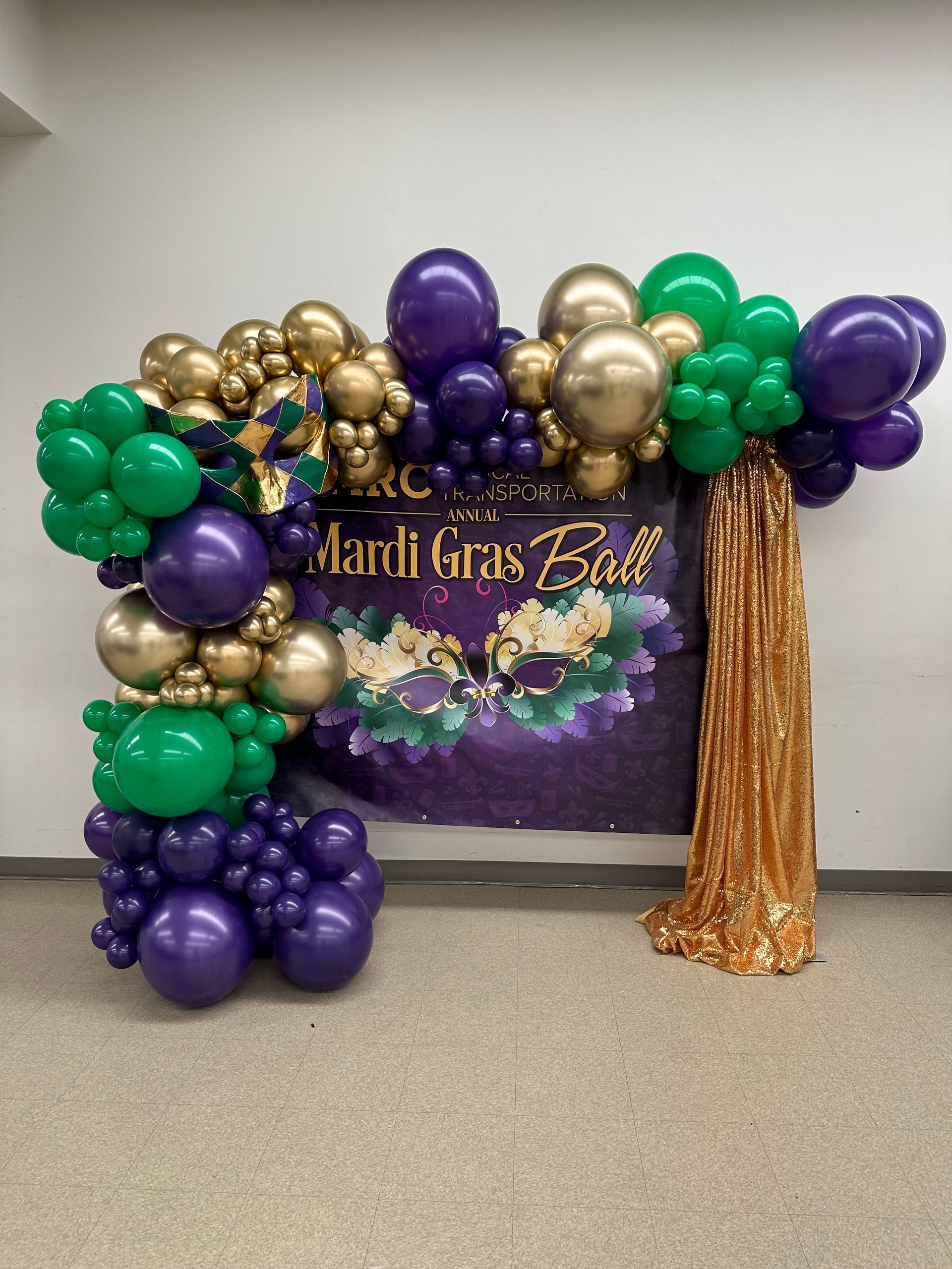 A mardi gras balloon arch with purple , green and gold balloons