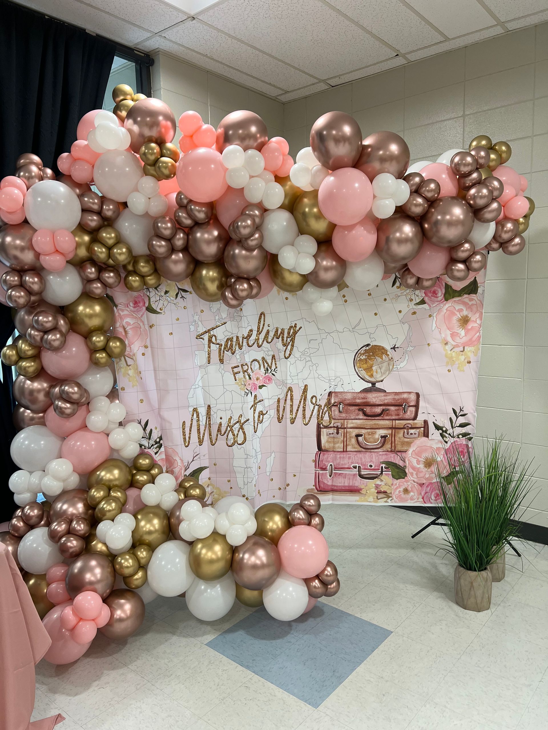 A bunch of pink and gold balloons are hanging on a wall