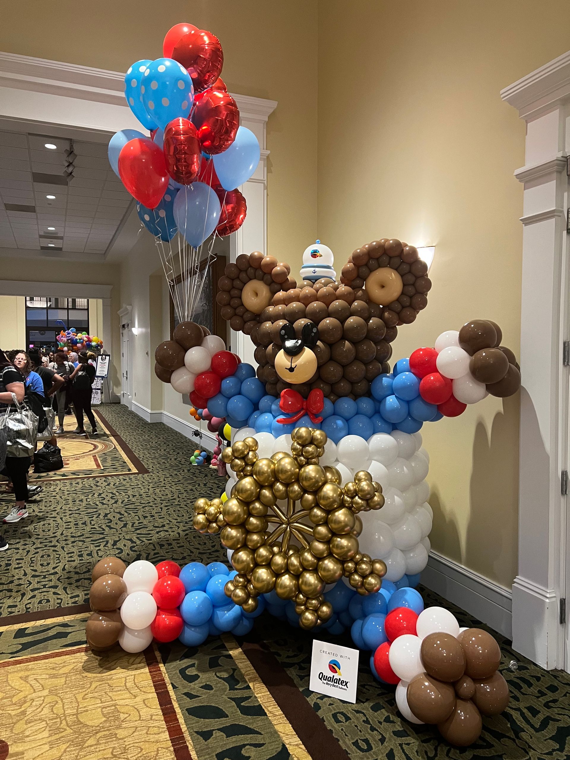 A teddy bear made out of balloons is holding a snowflake.
