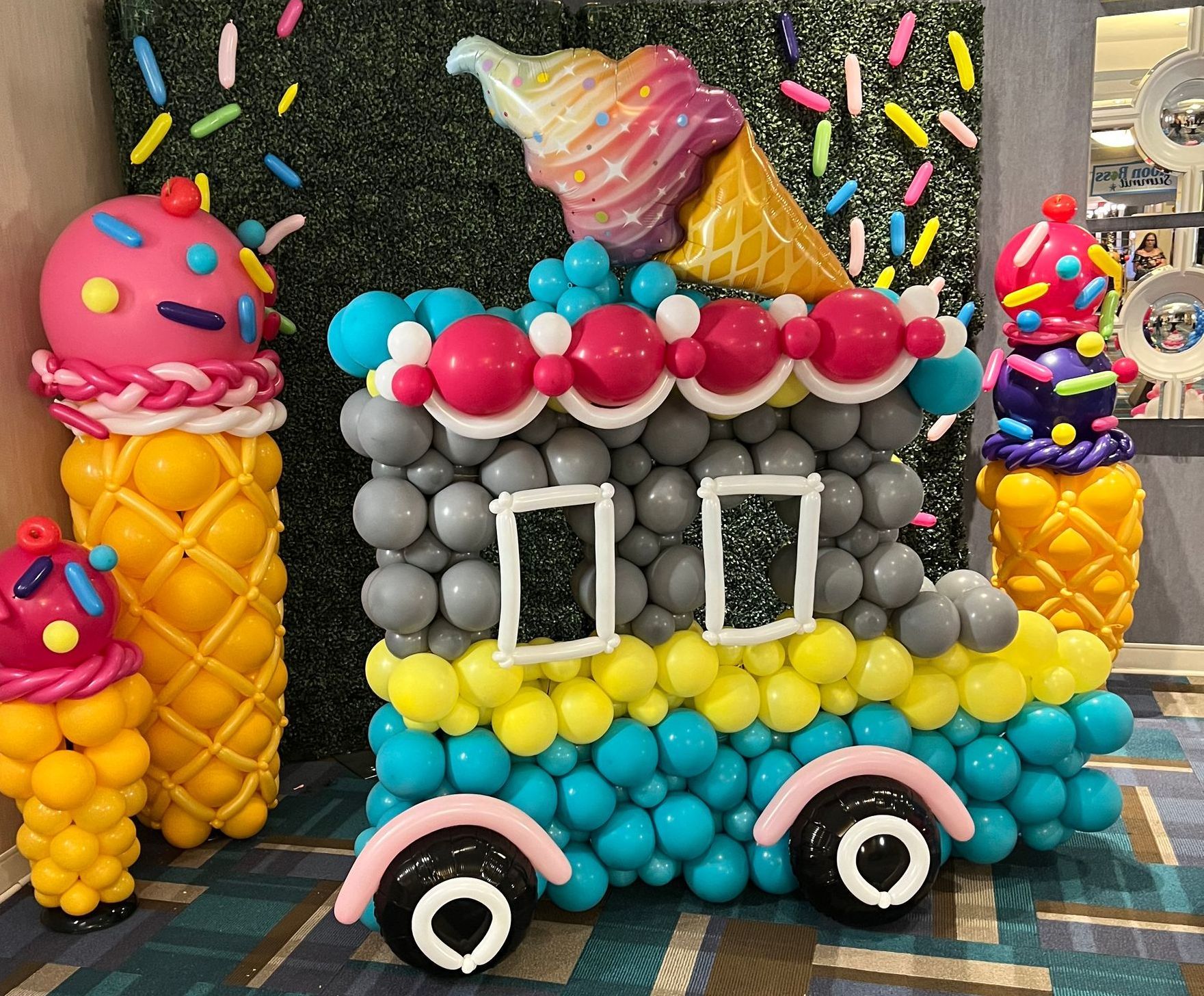 An ice cream truck made out of balloons with ice cream cones and sprinkles.