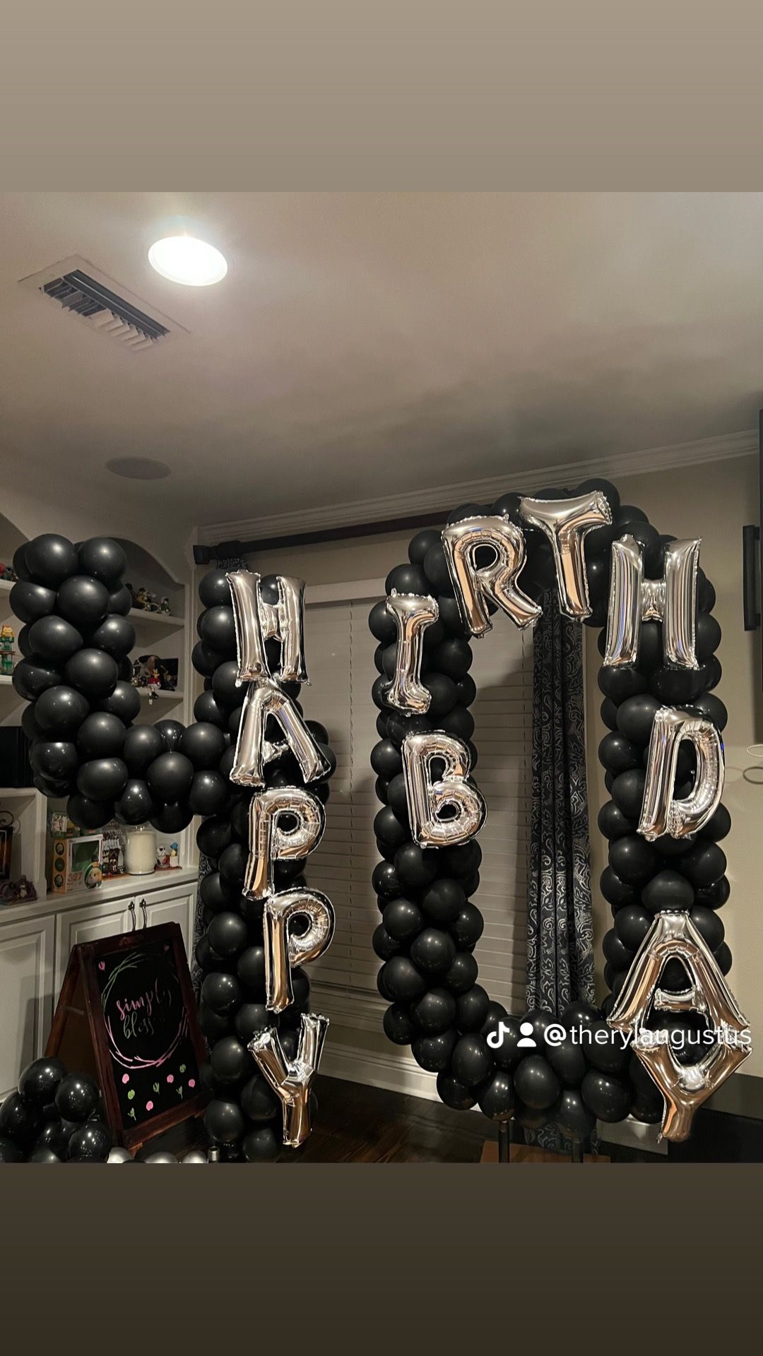 A room decorated with black balloons and silver balloons that spell out happy birthday.