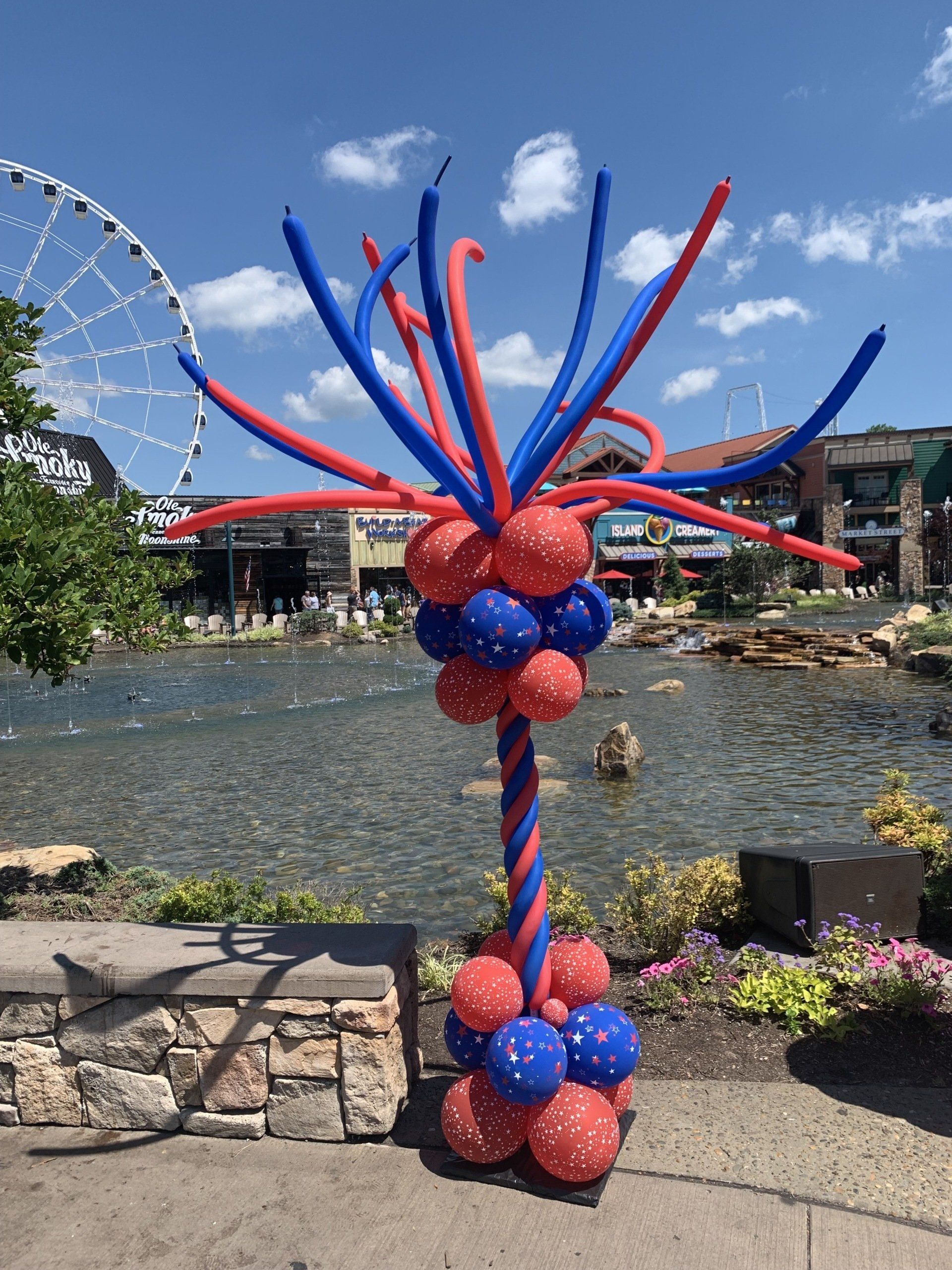 A tree made of red and blue balloons in front of a ferris wheel.