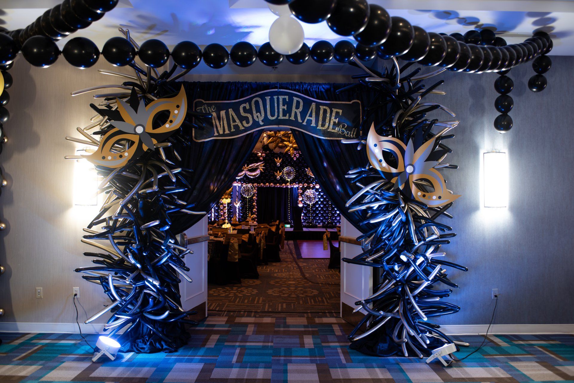 A room decorated for a masquerade party with balloons and masks.