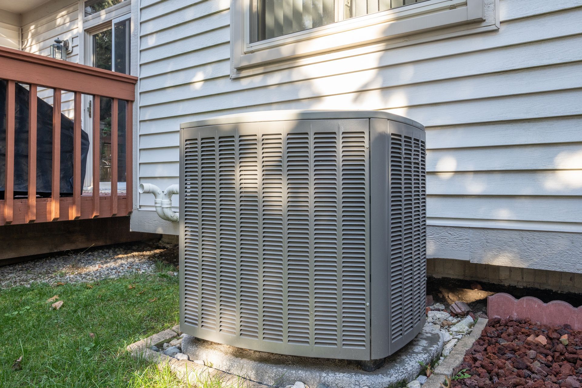 A large air conditioner is sitting on the side of a house.