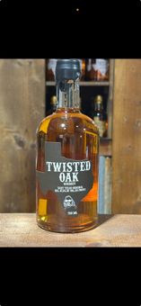 A bottle of twisted oak whiskey is sitting on a wooden table.