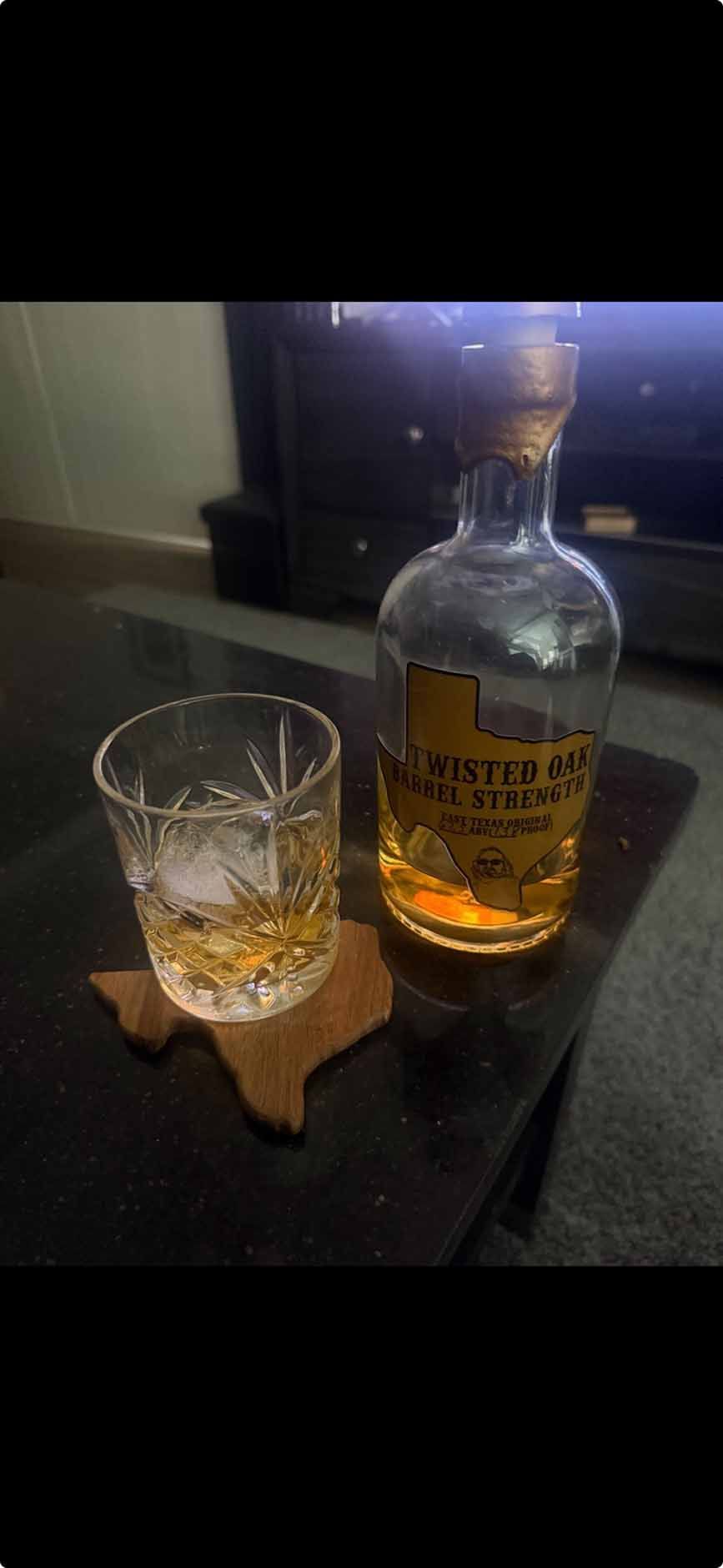 A bottle of whiskey and a glass of whiskey are on a table.