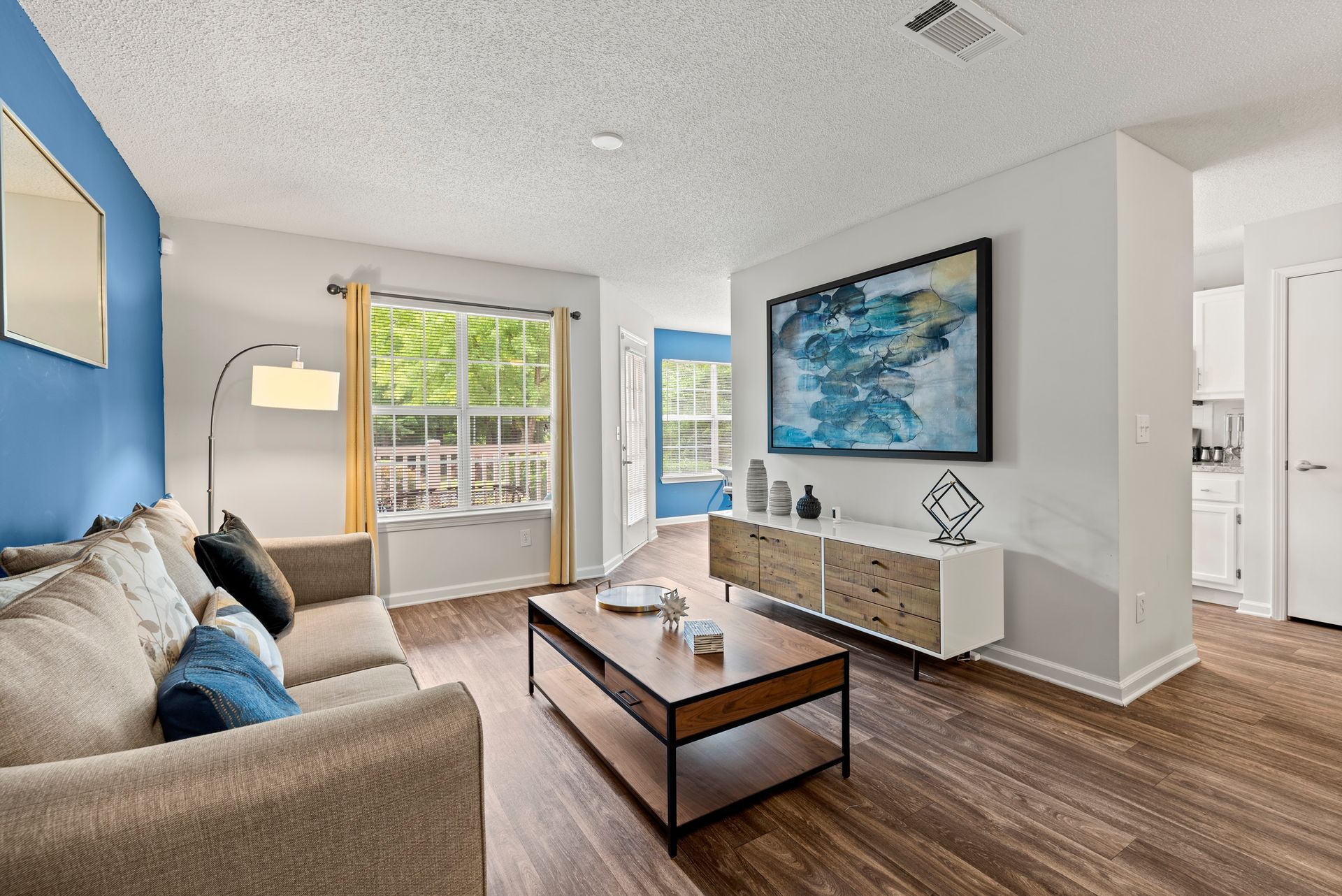 Living room with wood floors wall art, brown sofa at The Aubrey