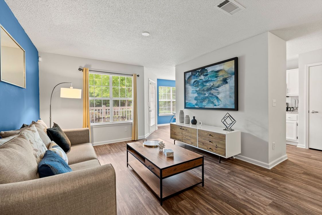 Living room with wood floors wall art, brown sofa at The Aubrey