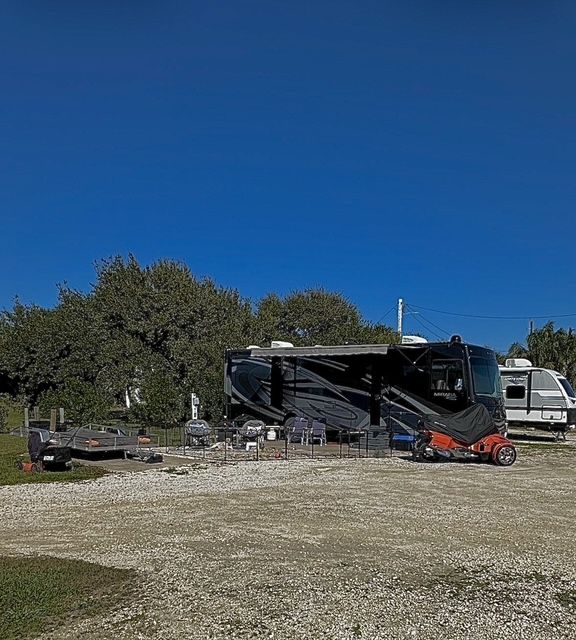 RV and trailer parked at a campsite on a sunny day.