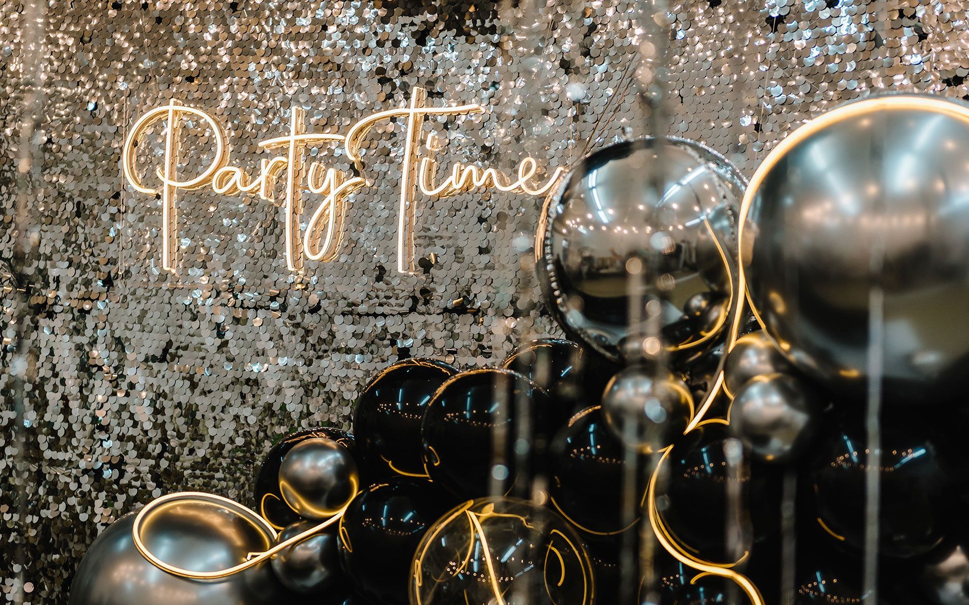 A bunch of balloons are sitting in front of a sign that says party time.