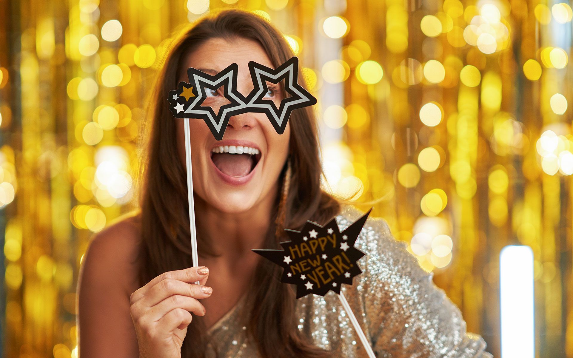 A woman is holding a pair of glasses on a stick in front of her eyes.