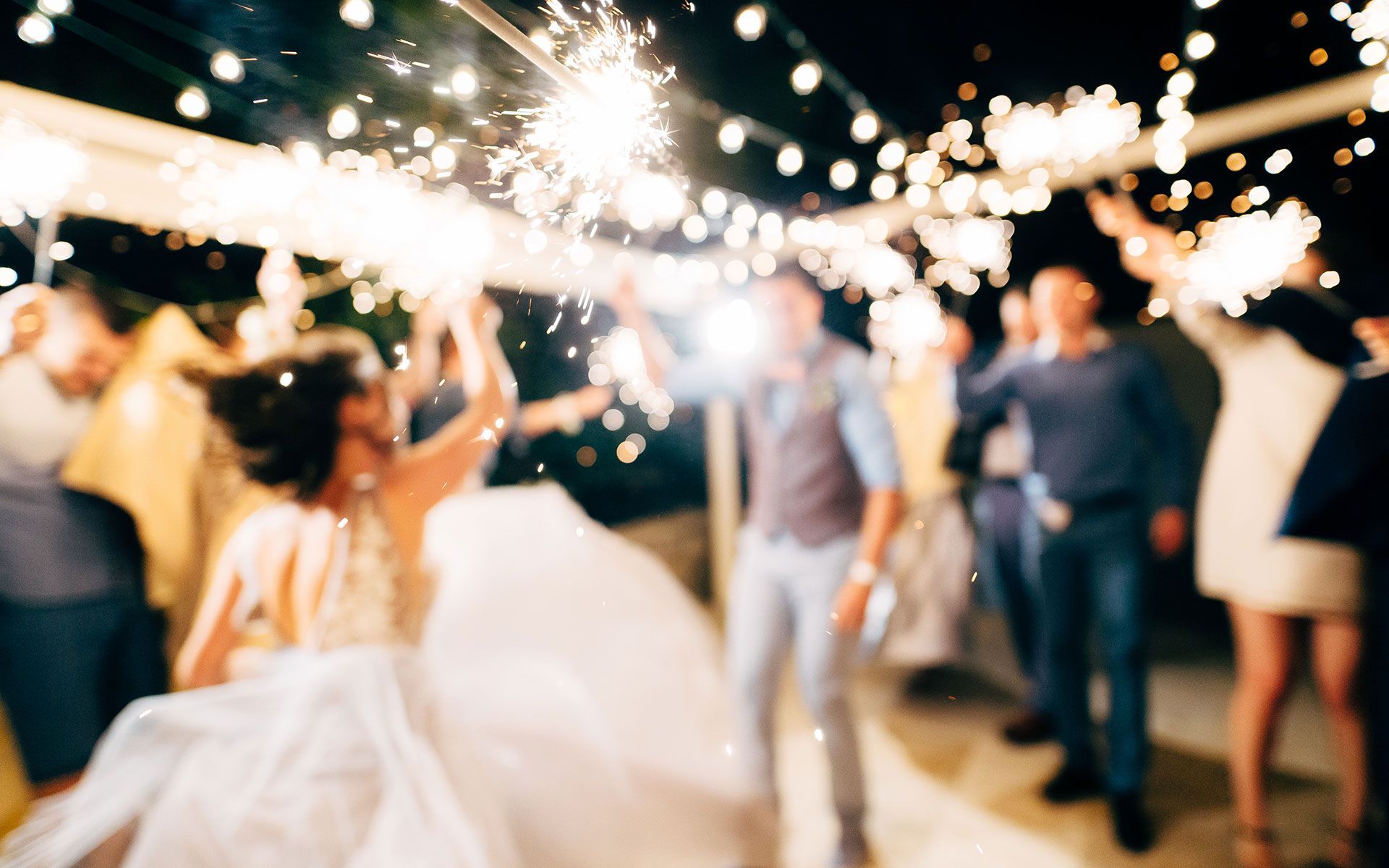 A bride and groom are dancing with sparklers at their wedding reception.