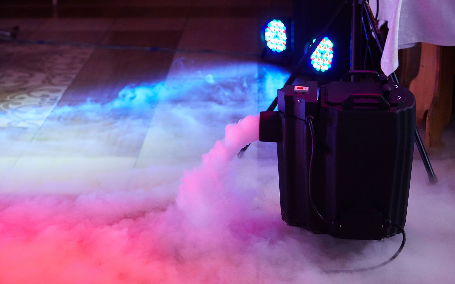 A machine is making smoke on the floor in a dark room.