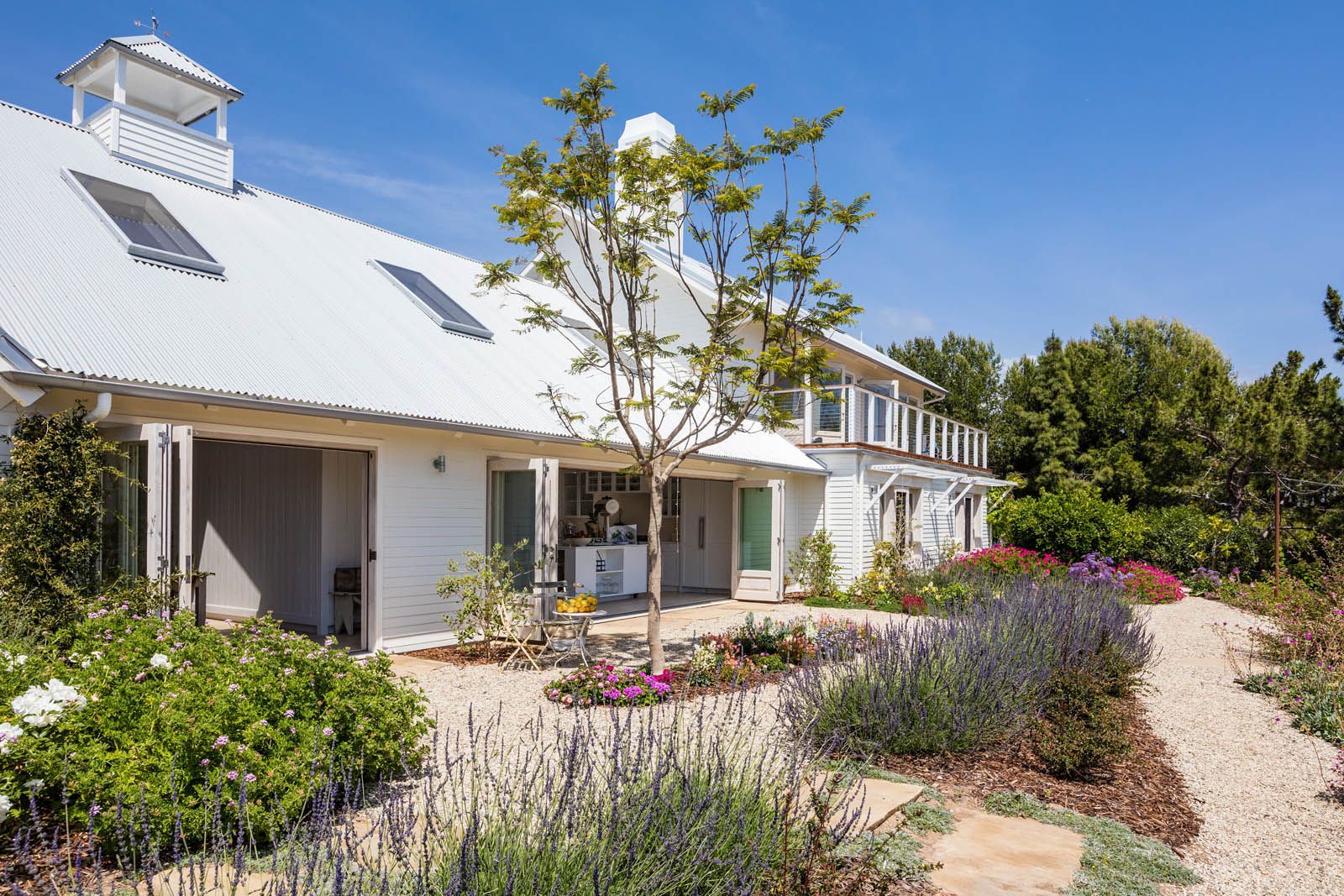 A white house with a lot of flowers in front of it