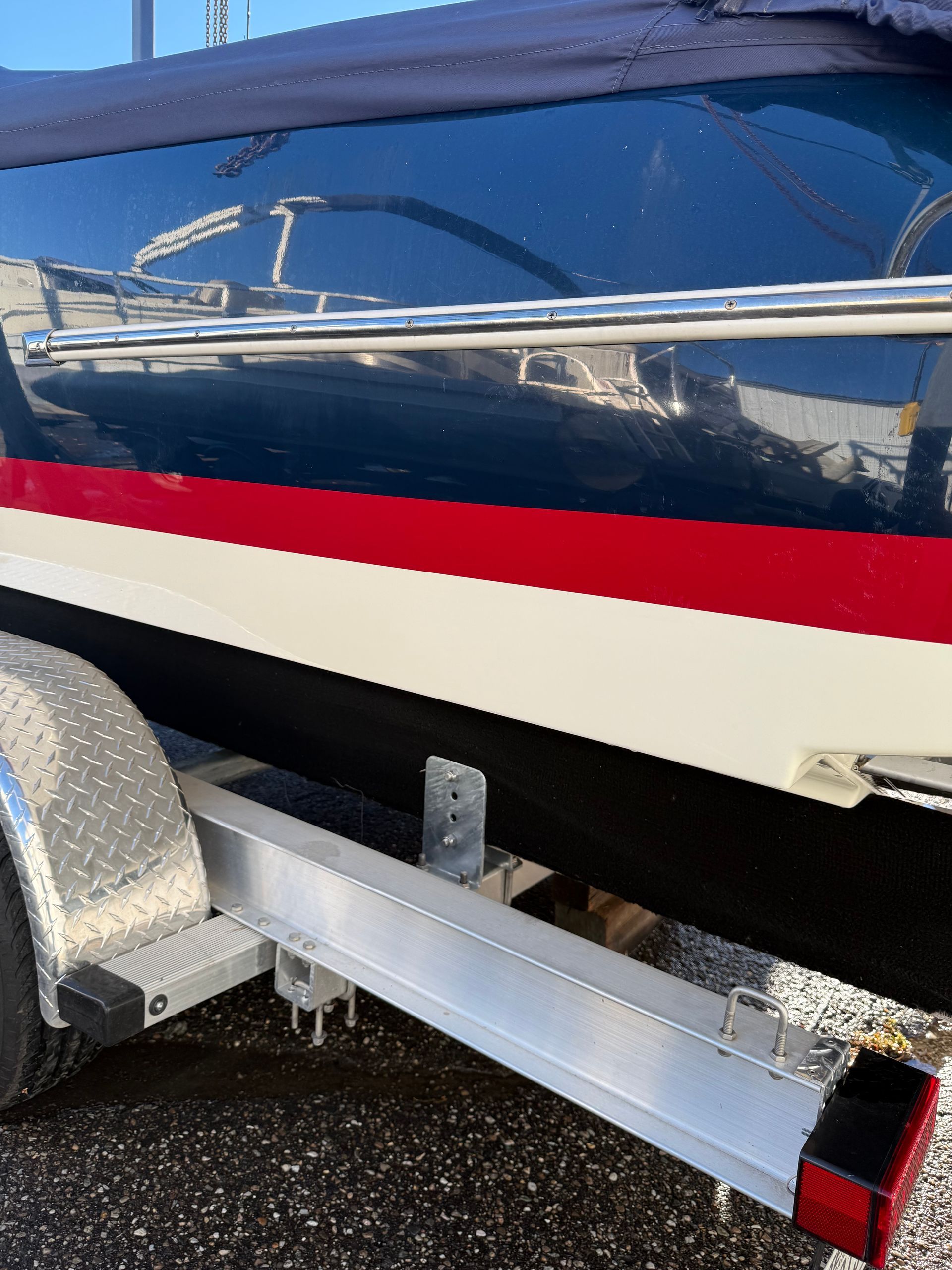 Blue and white boat with red stripe on a trailer.