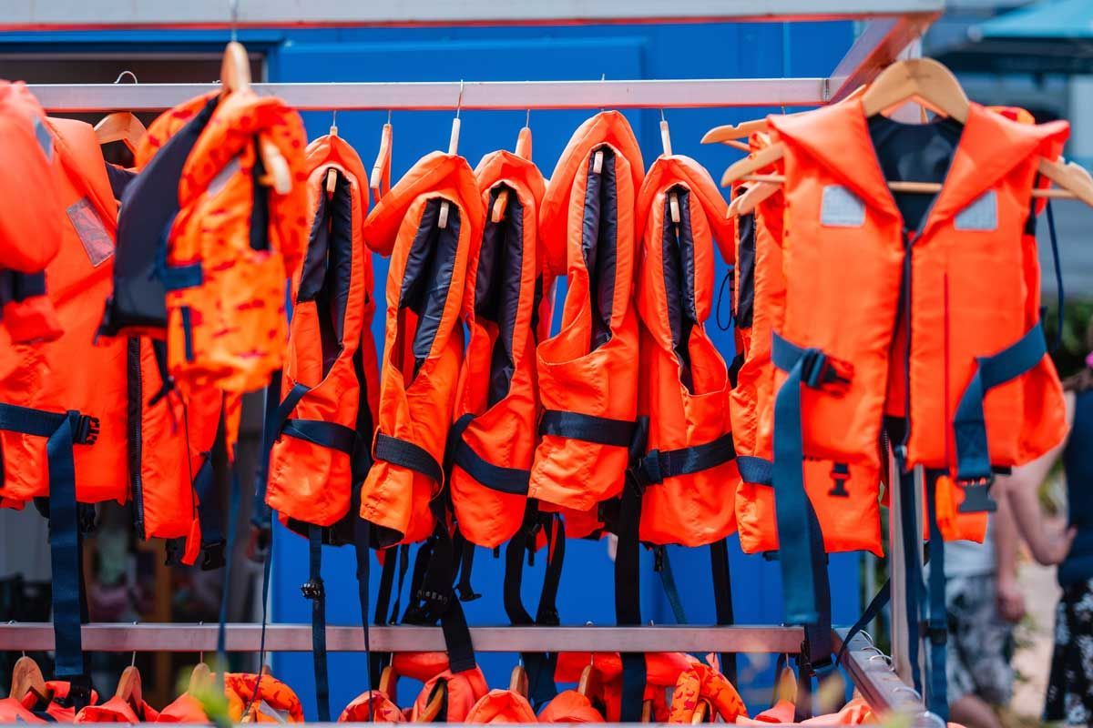 Row of orange life jackets hanging on a rack.