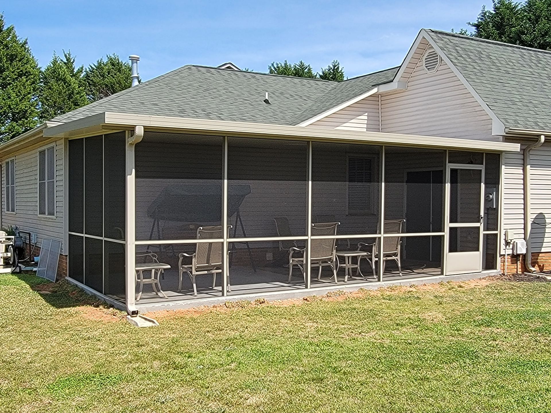A screened in porch in the backyard of a house