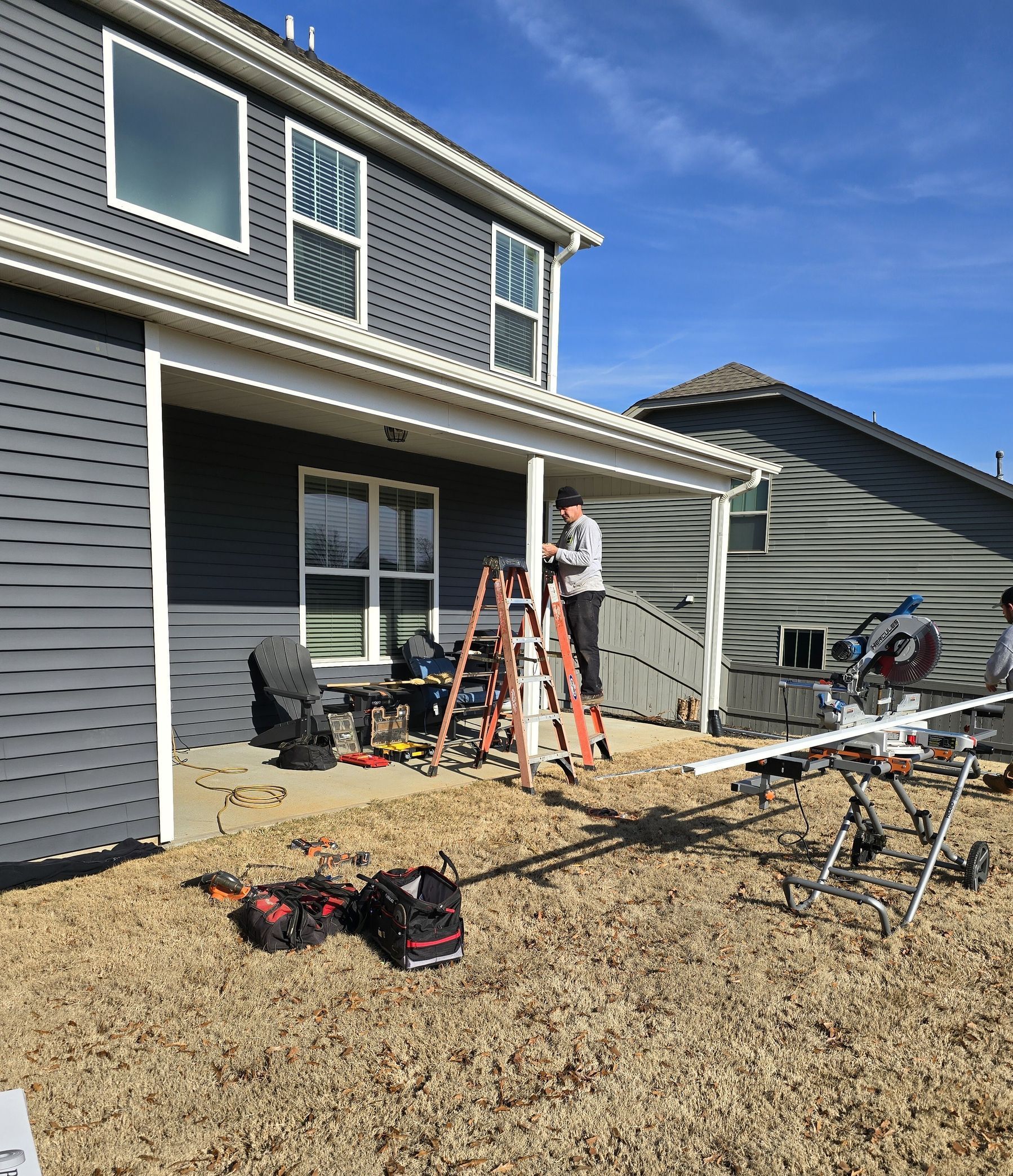 A man is standing on a ladder in front of a house.