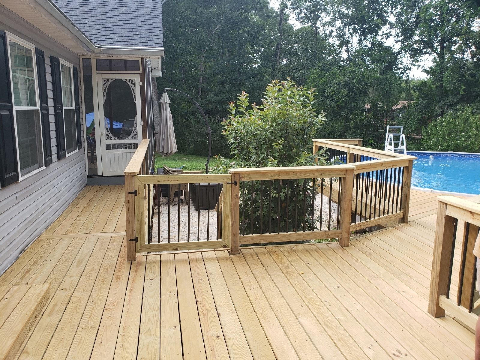 A wooden deck with a fence and a swimming pool in the background.
