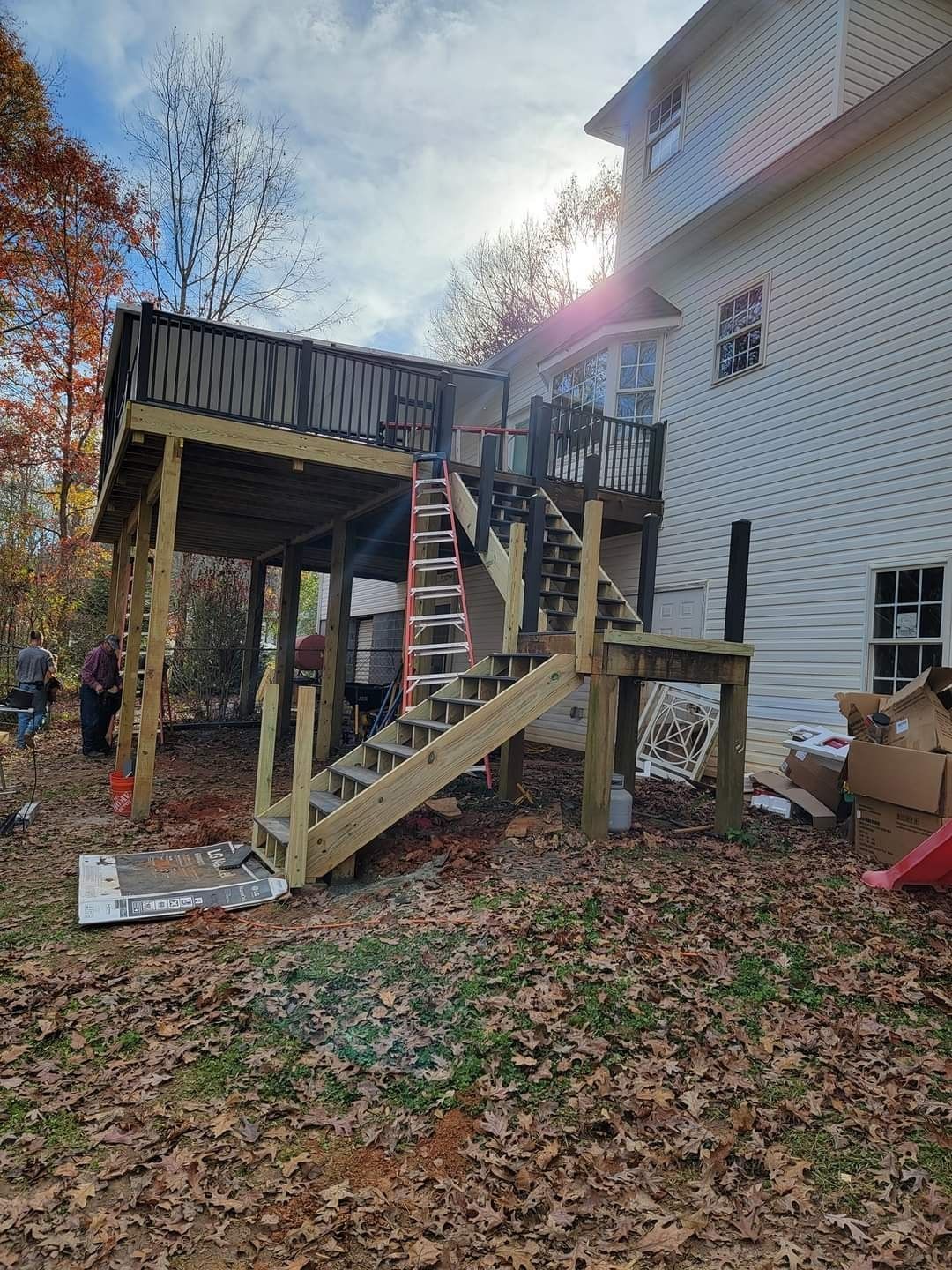 A wooden deck with stairs is being built in front of a house.