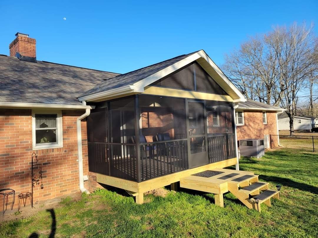 A screened in porch on the side of a brick house.