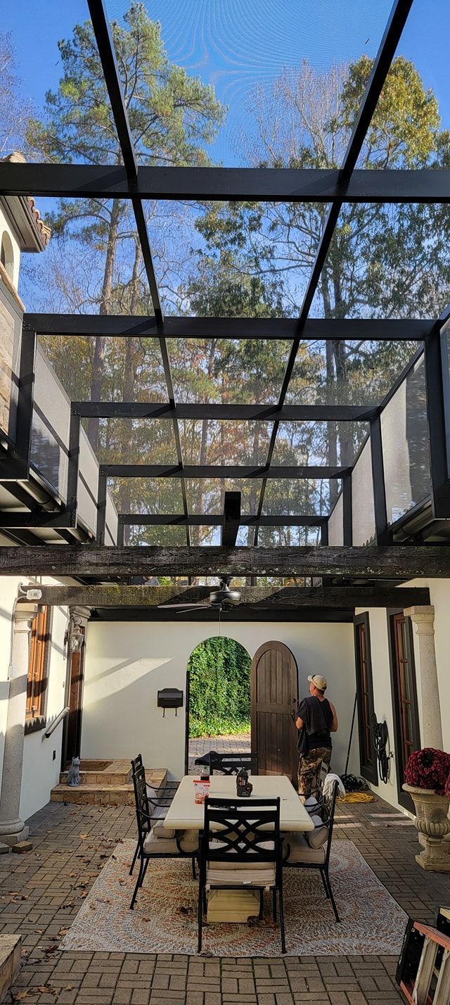 A patio with a table and chairs under a glass roof.