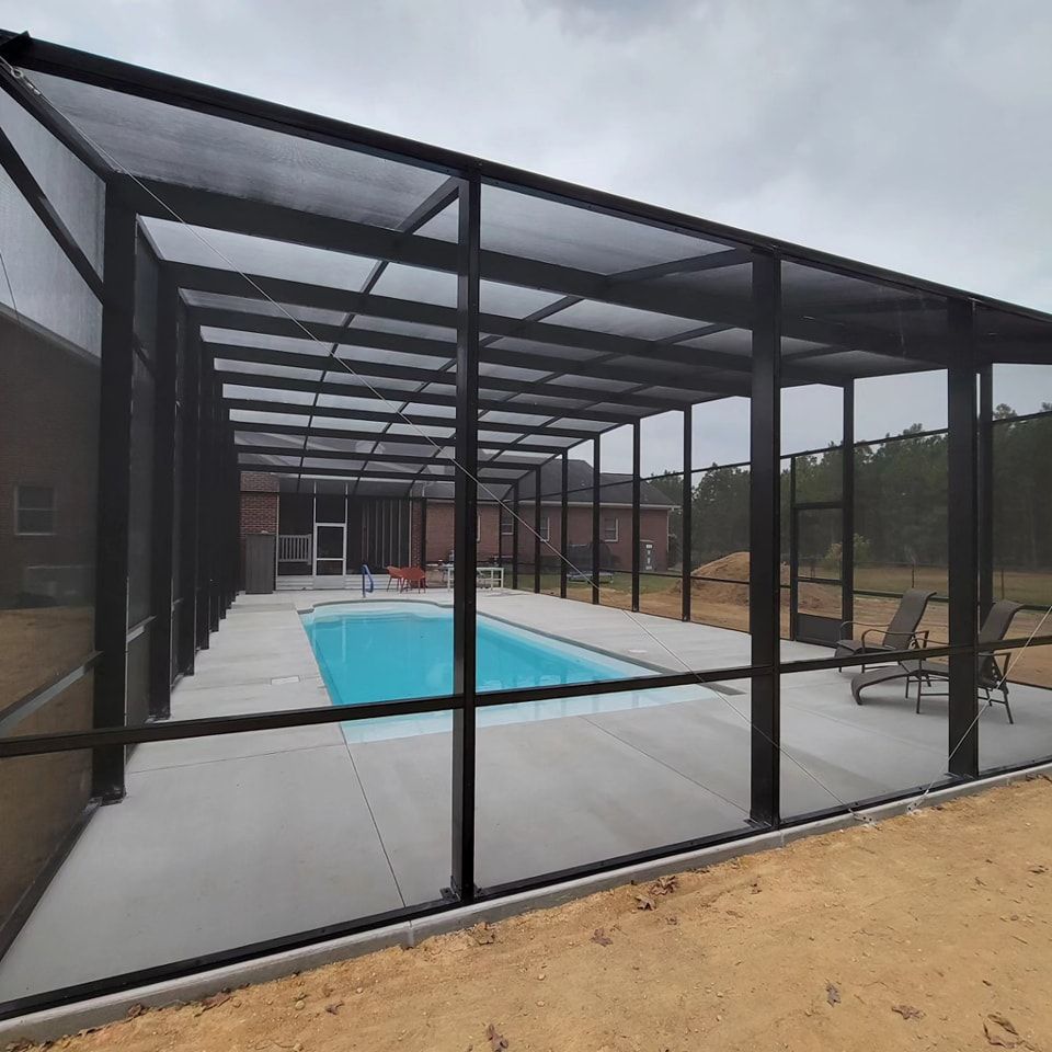 A screened in area with a swimming pool and chairs