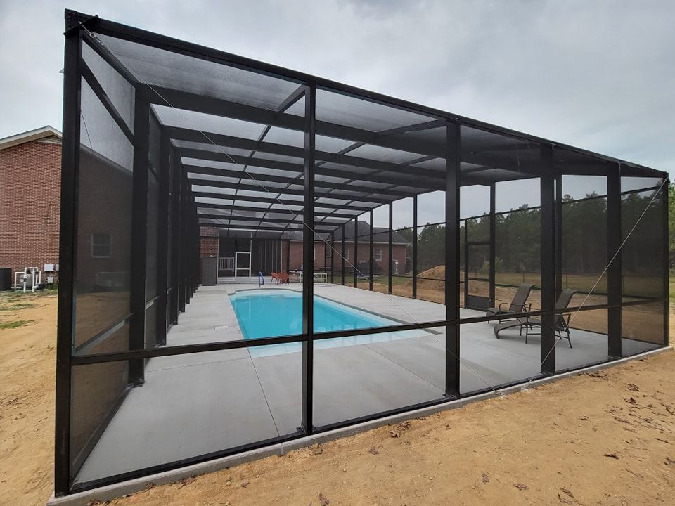 A screened in swimming pool with a brick building in the background.
