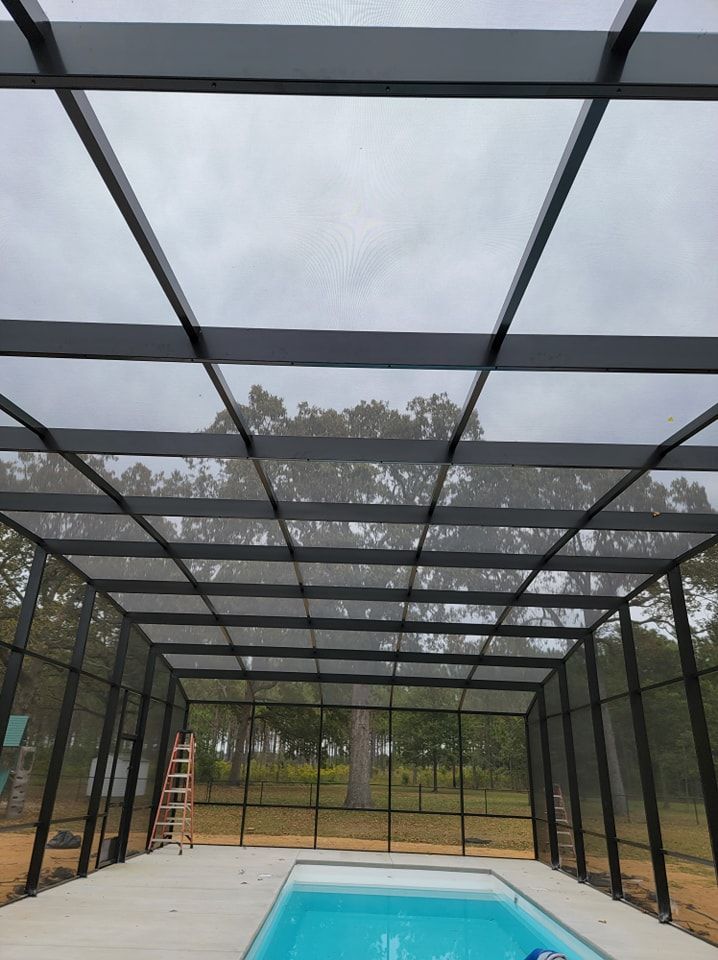 A swimming pool under a screened in area with a ladder.