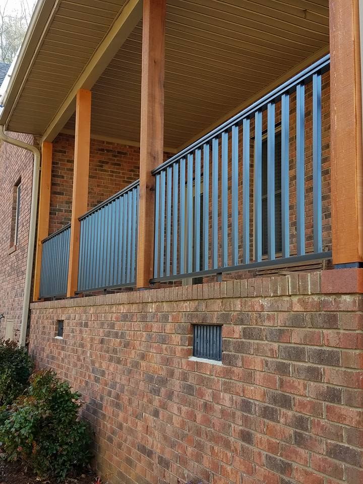 A brick house with a porch with a metal railing