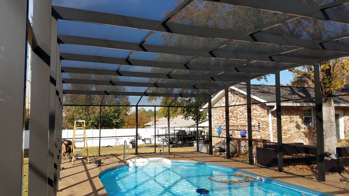 There is a swimming pool under a screened in porch.