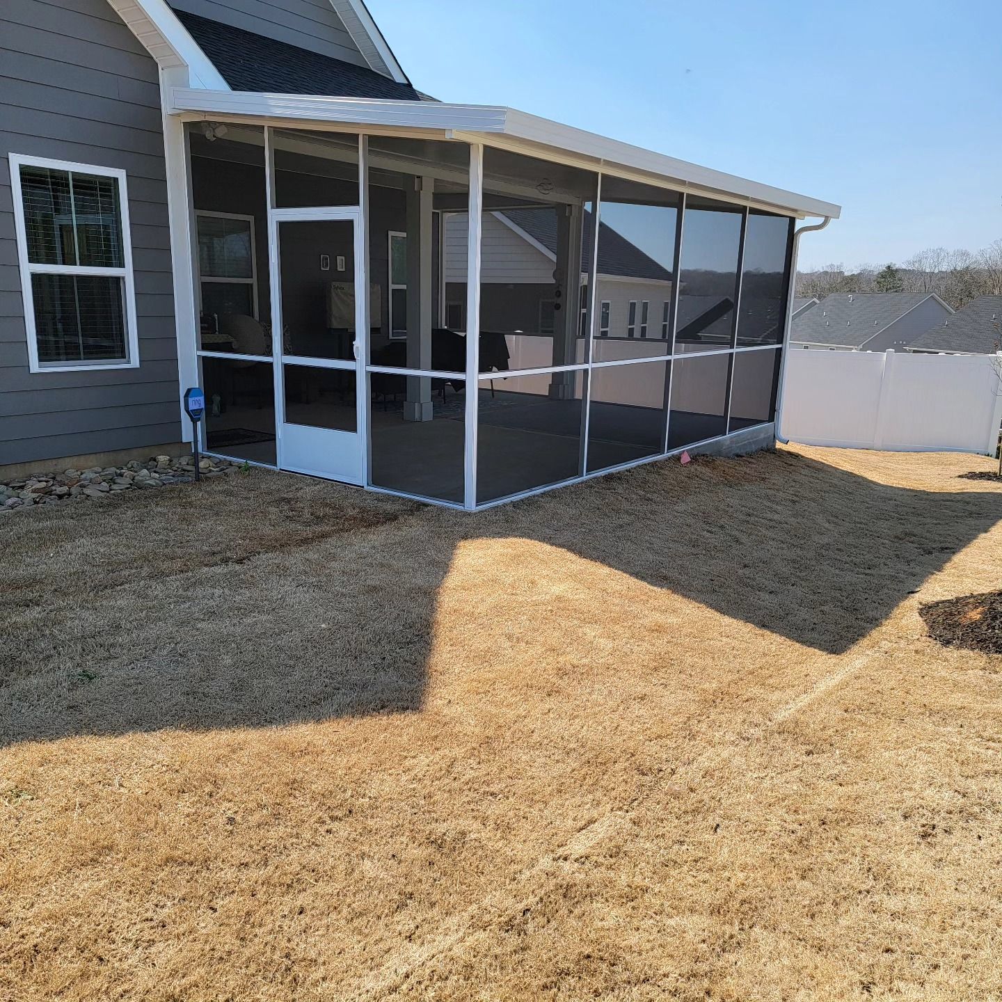 A screened in porch in the backyard of a house